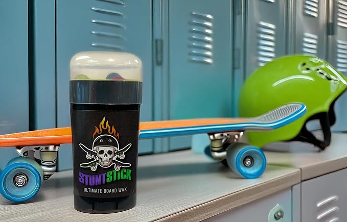 Stunt Stick Skateboard Wax beside a vibrant skateboard and helmet, perfect for a stylish grind.